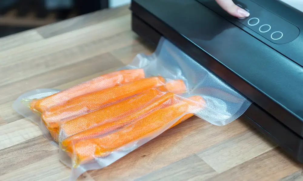 Das Foto zeigt Karotten die gerade in einen Vakuumbeutel eingeschweißt werden.